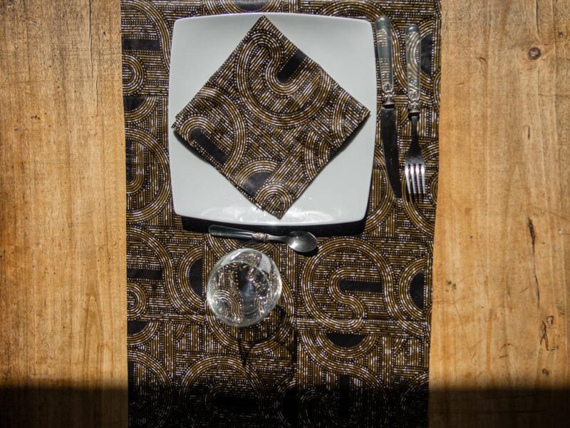 Chemin de table aux motifs bogolan noir et dorés, accompagné de ses serviettes assorties