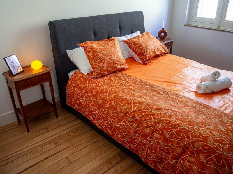 Parure de lit orange avec des motifs ouest africains emblématiques avec une housse de couette et des coussin assortis en wax