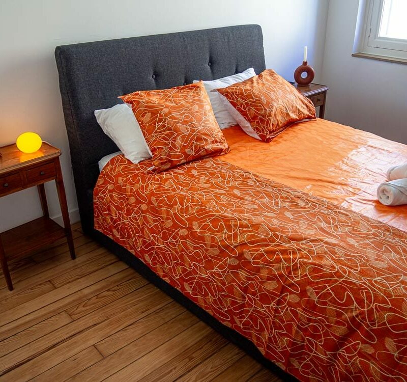 Parure de lit orange avec des motifs ouest africains emblématiques avec une housse de couette et des coussin assortis en wax