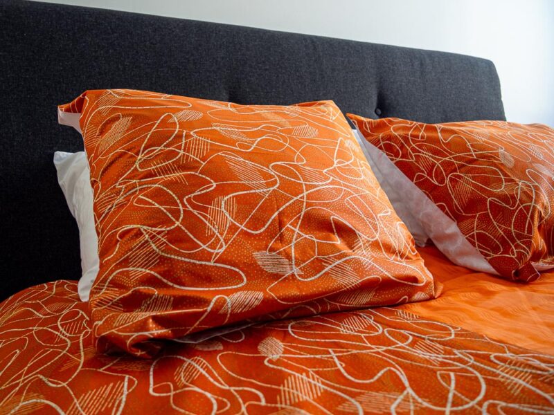 Parure de lit orange avec des motifs ouest africains emblématiques avec une housse de couette et des coussin assortis en wax