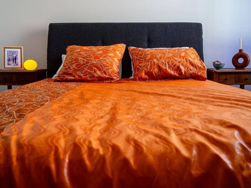 Parure de lit orange avec des motifs ouest africains emblématiques avec une housse de couette et des coussin assortis en wax