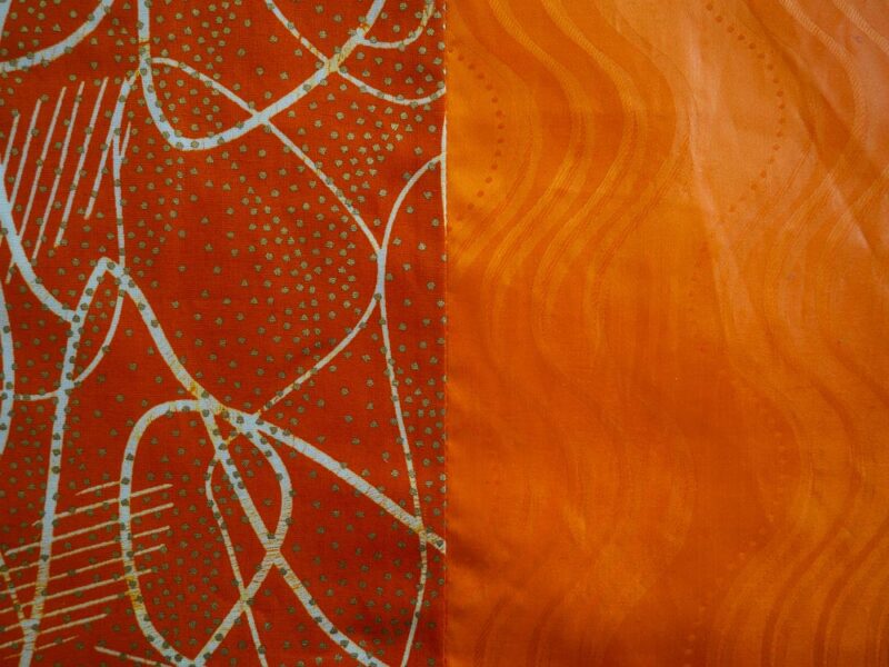 Parure de lit orange avec des motifs ouest africains emblématiques avec une housse de couette et des coussin assortis en wax - vue de près