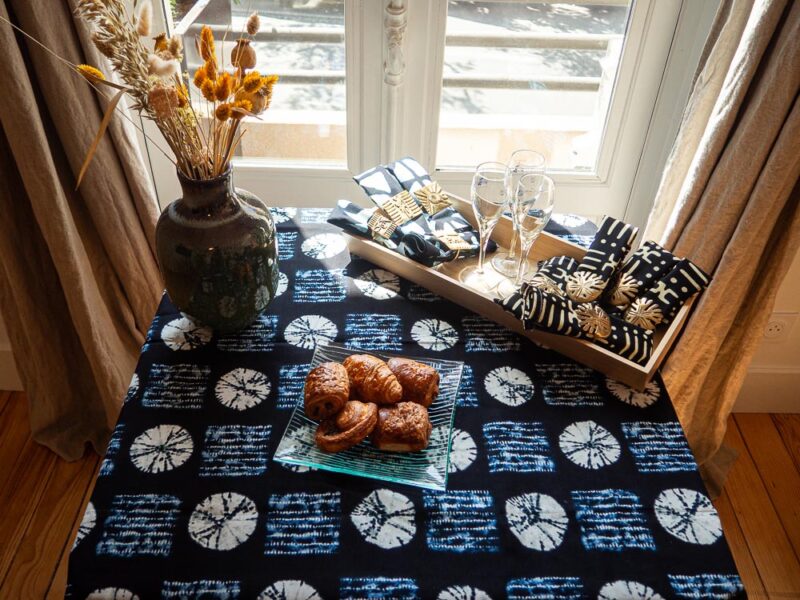 Nappe bleue aux motifs bogolan, accompagnée de sets de serviettes bleu et noires