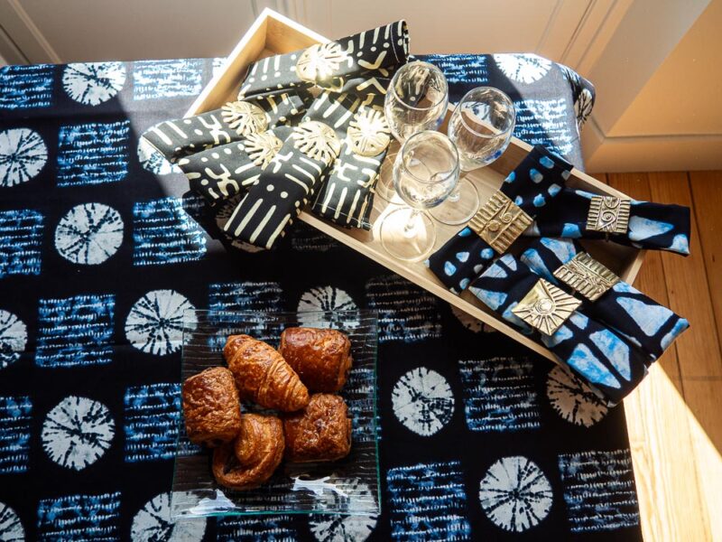 Nappe bleue aux motifs bogolan, accompagnée de sets de serviettes bleu et noires